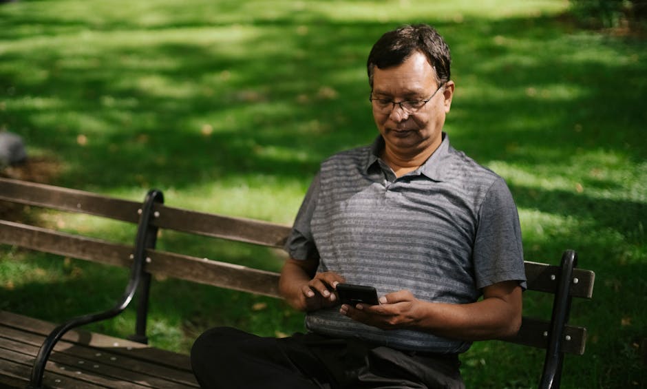 이미지 - a-man-carefully-adjusts-his-smartphone-magnifier-on-a-sunny-park-bench-to-read-tiny-text-clearly-png